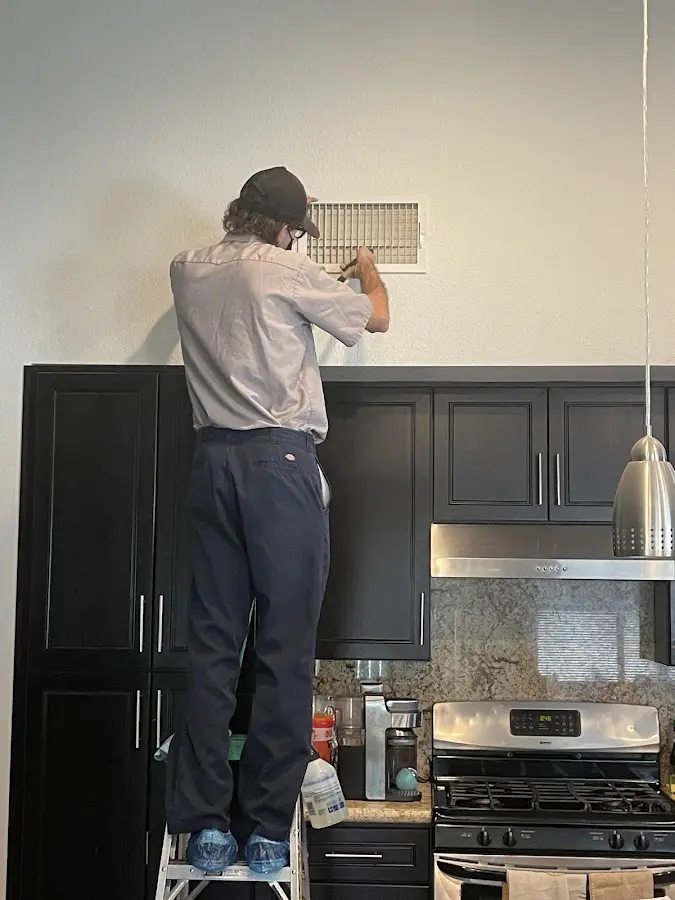Technician inspecting an air vent during HVAC service in St. Joseph